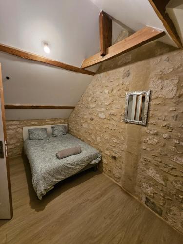 a bedroom with a bed in a stone wall at Cœur de Villers in Villers-Saint-Paul