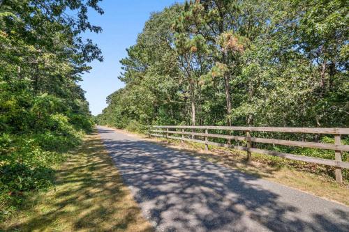 a road with a fence on the side at Bring your pups to Chatham Direct access to the Cape Cod Rail Trail in Chatham