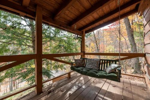 a porch with a green couch on a wooden deck at Outdoors Sleeps7 Family Getaway Fun Arcade Villa in Rockbridge
