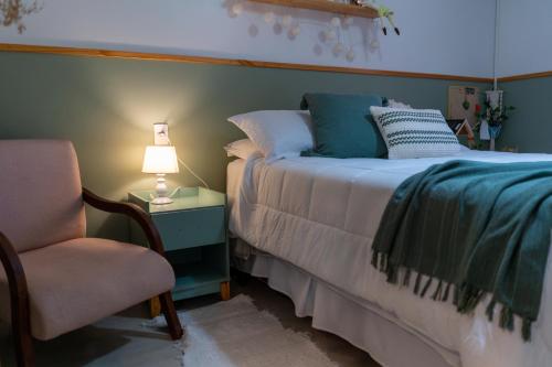 a bedroom with a bed and a chair and a lamp at Refugio Na Praia Hospedagem - Guarda Do Embaú in Guarda do Embaú