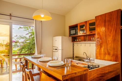 a kitchen with a wooden table and a refrigerator at Villa das Palmeiras Jeri in Jericoacoara
