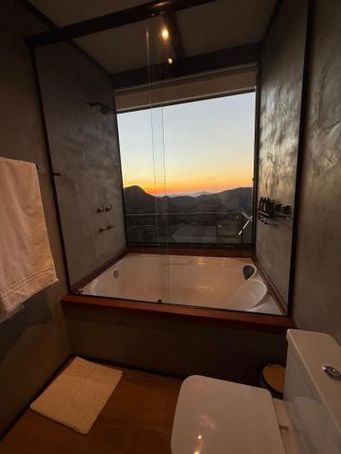 a bathroom with a tub and a toilet and a window at Cabana Encanto do Sapucaí in São Bento do Sapucaí