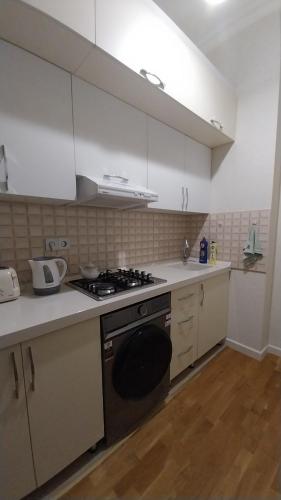 a kitchen with white cabinets and a stove top oven at Banu House in Sumqayyt