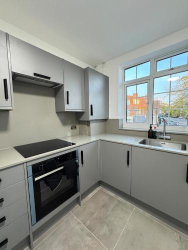 a kitchen with white cabinets and a sink and a window at Twos Company in Brookmans Park