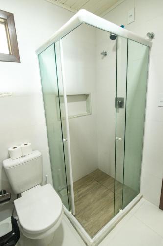 a bathroom with a toilet and a glass shower at Pousada Aroeira in Morro de São Paulo