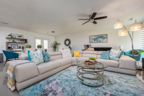 a living room with a white couch and a glass table at UF SUNSHINE HOUSE - Patio & BBQ - Chef Kitchen - EV Car Station - Upscale Neighborhood! in Gainesville