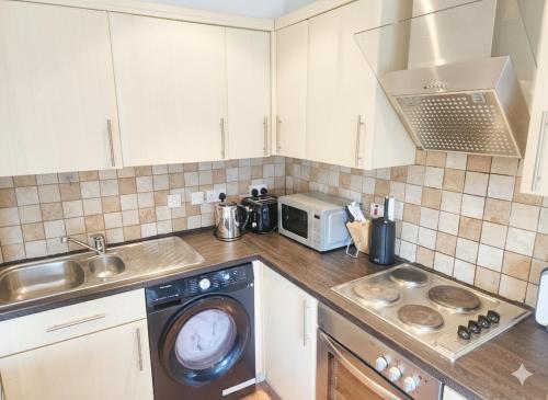 a kitchen with a washing machine and a microwave at Stylish Flat on Cowley a Walk to Oxford Centre in Oxford