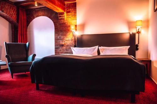 a bedroom with a large bed and a chair at Elbe Resort Alte Ölmühle in Wittenberge