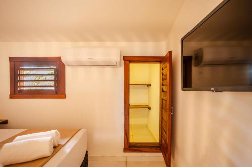 a bathroom with a mirror and a tv on the wall at Villa das Palmeiras Jeri in Jericoacoara