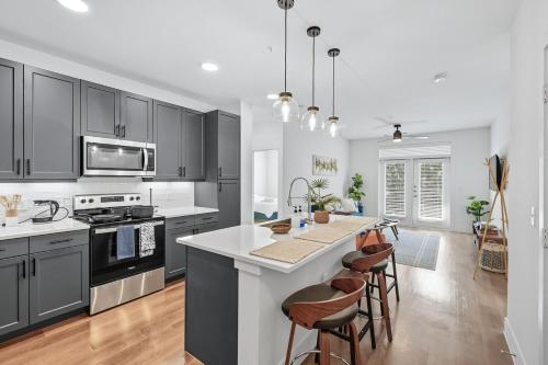 a kitchen with black cabinets and a kitchen island with bar stools at 336 Chic 2B2B Near Stockyards, Resort Style Pool & Gym, Golf Simulator, 7M to Dickies Stadium, 15M to AT&T stadium in Fort Worth