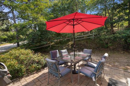 a table and chairs with a red umbrella at Classic Cape Great Location Dog Welcome in Wellfleet