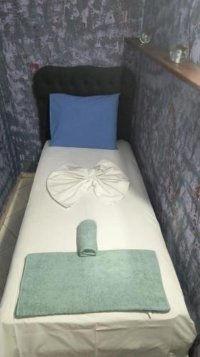 a bed with a blue pillow and a hat on it at War Bunker Hostel in Sarandë