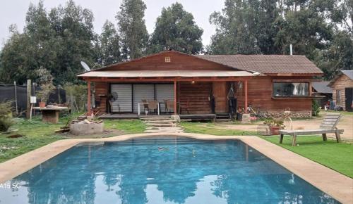 a log cabin with a pool in front of a house at Refúgiate con Nosotros Limache in Lo Narváez