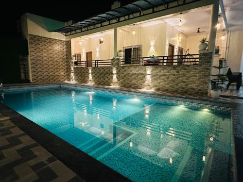 a swimming pool at night with lights on it at Aruna Farm House in Kakarmatha