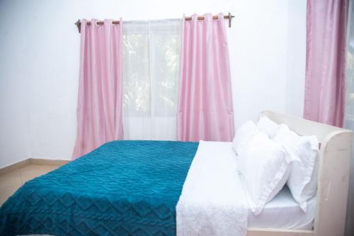 a bedroom with a bed with a blue blanket and a window at Ndoto Appartment in Ukunda
