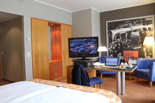 a hotel room with a bed and a desk with a laptop at Mercure Hotel & Residenz Berlin Checkpoint Charlie in Berlin