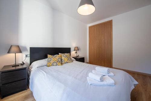 a bedroom with a white bed with towels on it at Barthe Holidays I Apartamento moderno en Arinsal 4PAX a pie de pistas, balcón con vistas y parking I Bosque in Arinsal