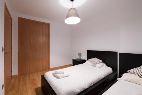a bedroom with two beds with white sheets at Barthe Holidays I Apartamento moderno en Arinsal 4PAX a pie de pistas, balcón con vistas y parking I Bosque in Arinsal