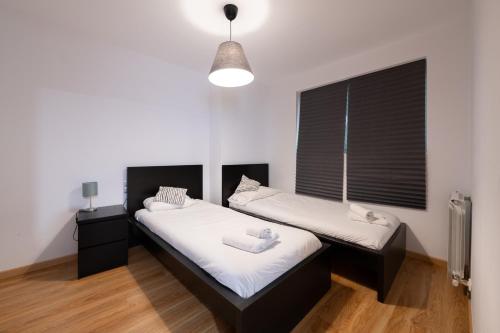 a room with two beds and a window at Barthe Holidays I Apartamento moderno en Arinsal 4PAX a pie de pistas, balcón con vistas y parking I Bosque in Arinsal
