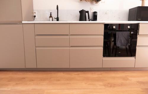 a kitchen with white cabinets and a black appliance at Le Mercœur - studio cosy - hyper centre Nantes in Nantes