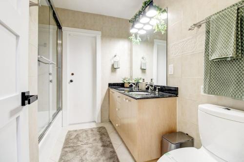 Un baño con lavabo, inodoro y espejo. en Vista Azul Lake Front Home with Hot Tub and Swim Spa, Fishing Dock, Gym, Game Room with Darts, Ping Pong, A Pool Table and more!, en Miami Lakes