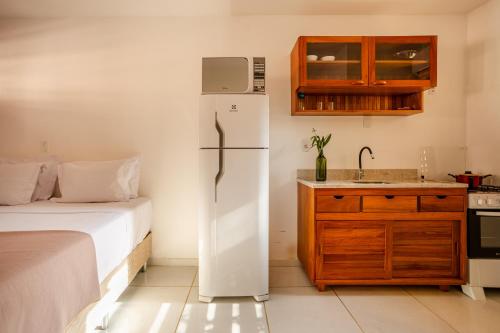 a kitchen with a refrigerator next to a bed at Villa das Palmeiras Jeri in Jericoacoara