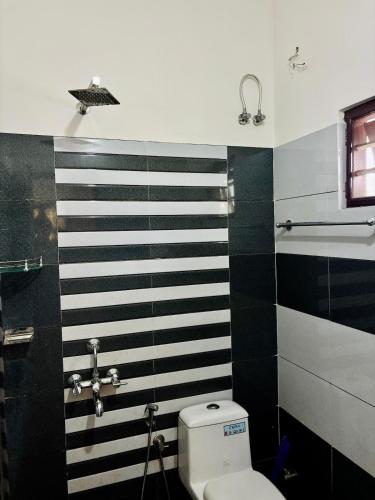 a bathroom with a toilet and black and white stripes at Spacious, Sweet home in town, in Kakkanad