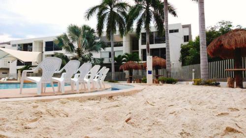 a group of white chairs sitting on the beach at Apartasol in Santa Fe de Antioquia