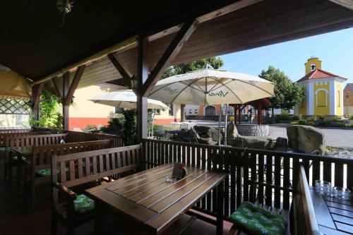 a wooden table and chairs with umbrellas on a patio at Šindlovská krčma in České Budějovice