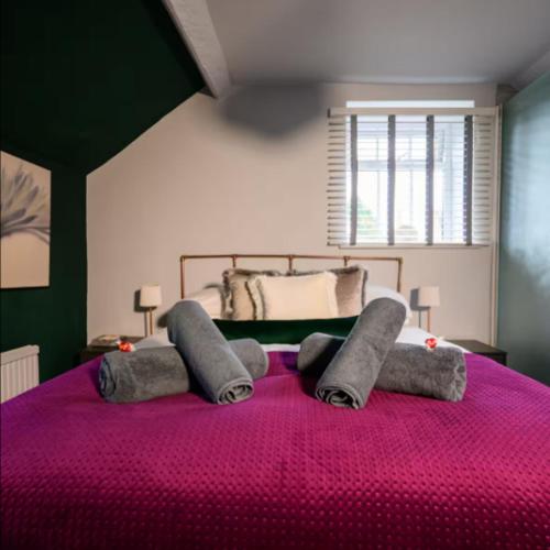 a bedroom with a large bed with a pink blanket at Cotswolds Corner Cottage in Moreton in Marsh