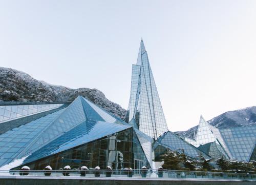 a building with two tall buildings with mountains in the background at Barthe Holidays I Apartamento moderno en Arinsal 4PAX a pie de pistas, balcón con vistas y parking I Bosque in Arinsal
