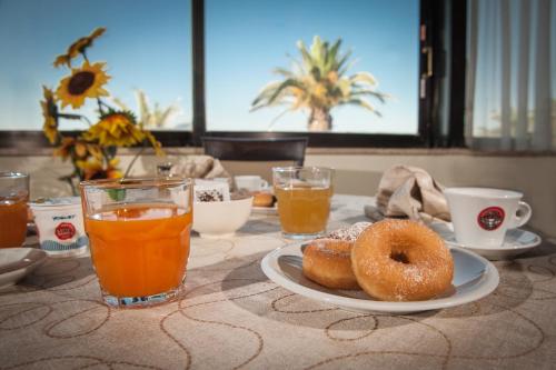 two donuts on a plate on a table with drinks at Hotel Villa Eleonora in Scauri