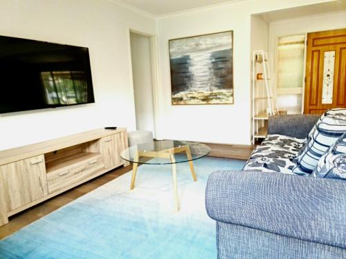 a living room with a couch and a tv at Close to beach and Mangrove walk in Batemans Bay