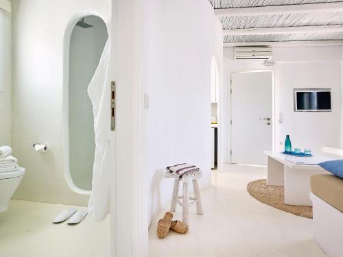 a white bathroom with a stool and a mirror at Delmar Apartments & Suites Milos - Delmar Collection in Pollonia