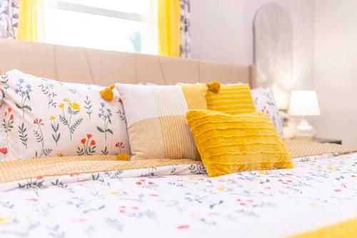 a bed with yellow and white pillows on it at 3BR, 1BA House Blocks from ETSU and Downtown in Johnson City