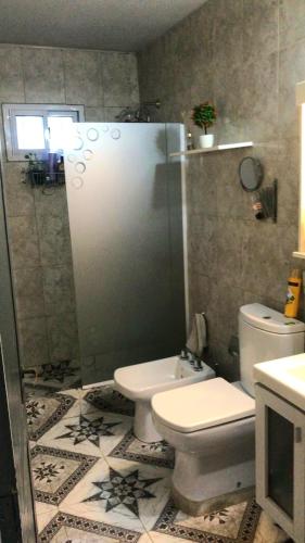 a bathroom with a toilet and a glass shower at Casa SIÓN in Ituzaingó