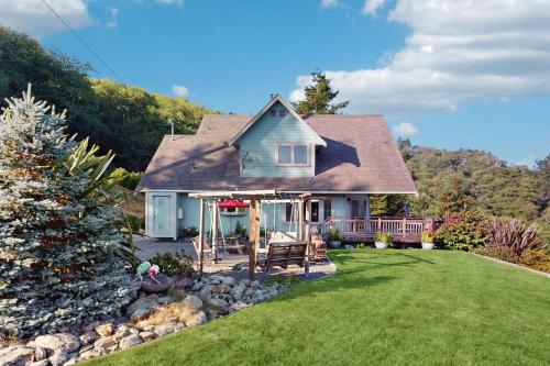 a blue house with a porch and a yard at Logan's Landing in Orick