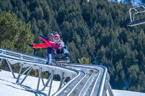 two people are sitting on a ski lift at Barthe Holidays I Apartamento con encanto en Arinsal 6PAX a pie de pistas I Balcón con vistas y parking I Milu in Arinsal