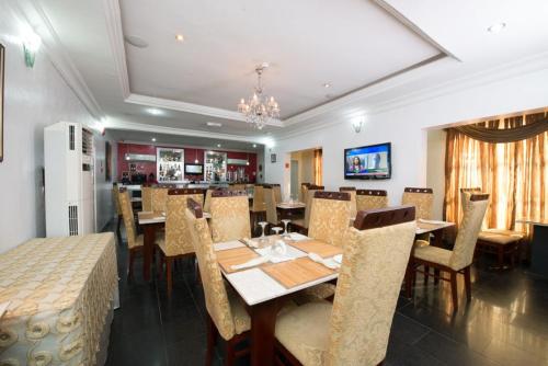 a dining room with tables and chairs and a kitchen at Adna Hotel in Lagos