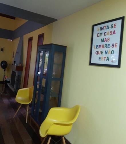 a room with two yellow chairs and a sign on the wall at Pousada Village Hostel in Petrópolis