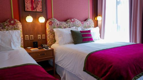 a bedroom with two beds with purple walls at Hotel Boutique Castillo Rojo in Santiago