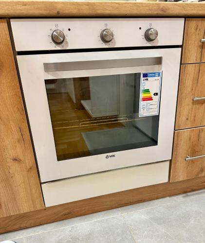 a white oven in a kitchen with wooden cabinets at Vidolux Studio in Niš