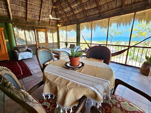 a dining room with a table and chairs and windows at Casa Maria en La Manzanilla in La Manzanilla