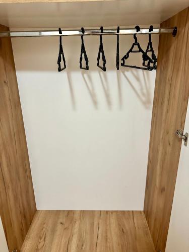 a closet with black hangers on a white wall at Vidolux Studio in Niš
