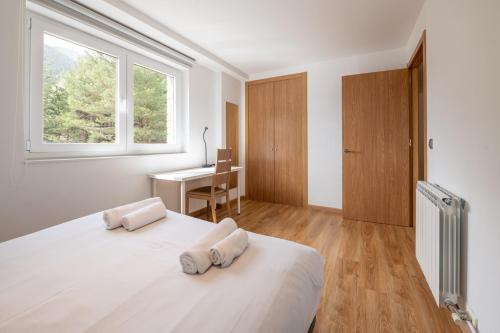 a bedroom with a bed and a desk and a window at Barthe Holidays I Apartamento Moderno en Arinsal 4PAX a pie de pistas I Balcón con vistas impresionantes al valle y parking I Guineu in Arinsal