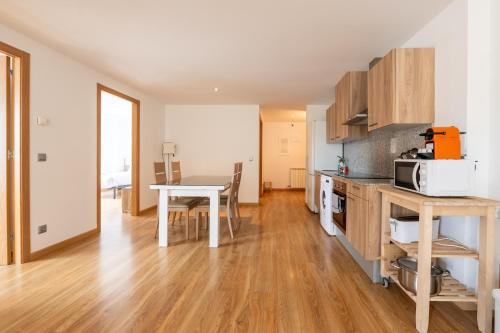 a kitchen and dining room with a table and a microwave at Barthe Holidays I Apartamento Moderno en Arinsal 4PAX a pie de pistas I Balcón con vistas impresionantes al valle y parking I Guineu in Arinsal