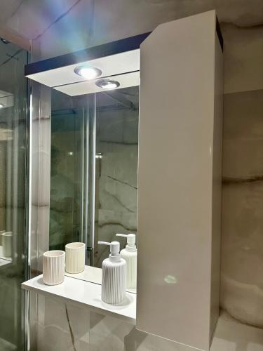 a bathroom with a mirror and white vases on a shelf at Vidolux Studio in Niš