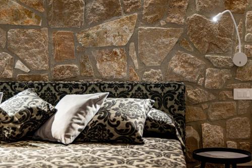 a couch with pillows and a stone wall at Dimora Milù in Foggia