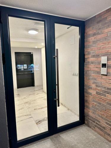 a glass door in a room with a brick wall at Vidolux Studio in Niš
