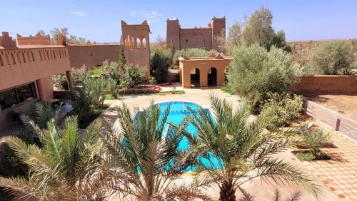 a pool in the middle of a yard with palm trees at Auberge Famille Benmoro in Skoura